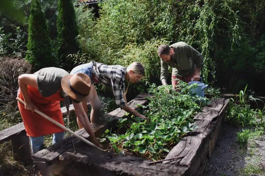 Glückliche junge und alte Menschen, die auf Gemeinschaftsfarm im Freien mit Gartengeräten arbeiten